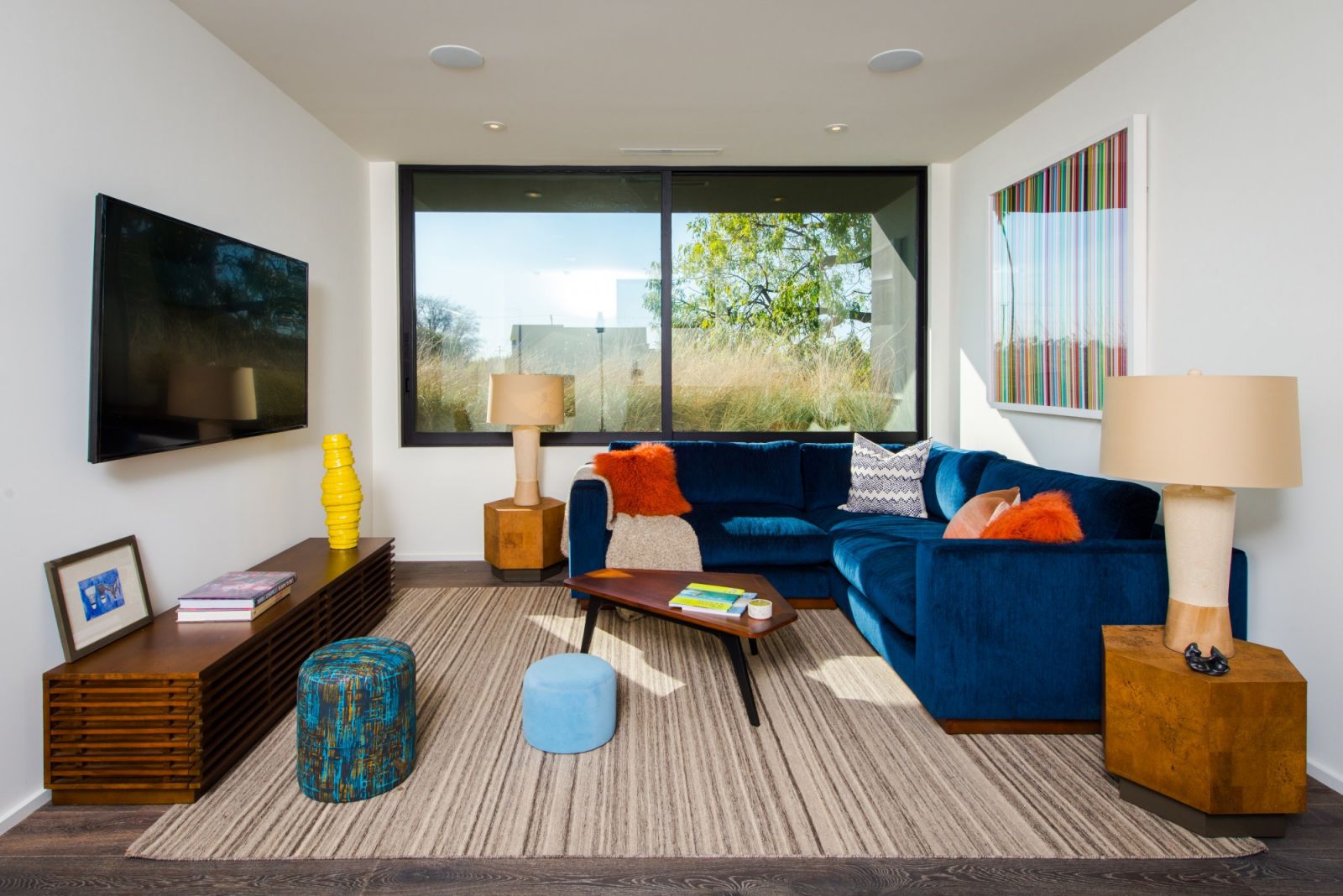 A light-colored painting will stand out against your blue couch's lack of textures and patterns. To diversify and tie the seraphic atmosphere of the space together, this homeowner brought in items in a variety of colors. Despite having a small living room, it appears to be having a lot of fun in this space. 