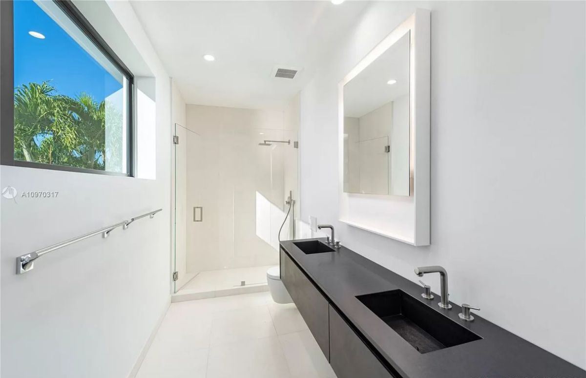 This small yet powerful contemporary bathroom incorporates many of the characteristics we've seen thus far, including black and white design, crisp geometrical shapes, and organic decorative accents. The unique black sink is a lovely addition—its form echoes minimalism.