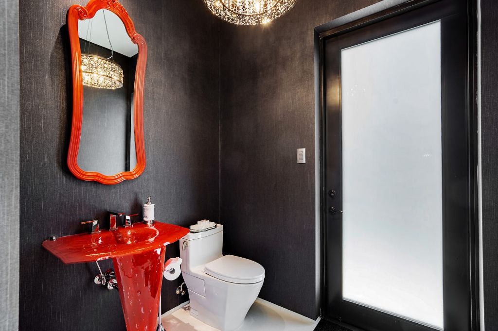 With the exception of the double vanity unit, which has a dramatic red-painted finish, this bathroom is entirely neutrals. This bathroom's dark grey wall is offset by the vibrant red vanity unit, constructed for impact, in a family home full of charm, character, and color.