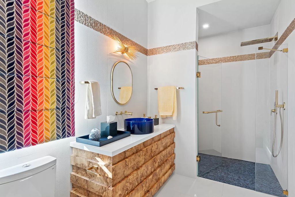 Natural stone trim complements white tile. Thin moldings split tile lines and highlight the transition between the backsplash and the white wall here. Honey-colored grout complements the space's neutral color palate while warming up the typical bathroom backsplash