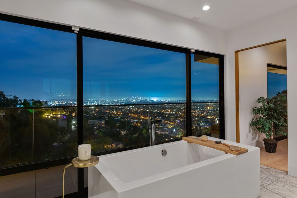 A floating vanity makes the space appear larger, wall-sized windows make the bathroom appear to be part of the landscape, and the translucent freestanding tub is nearly invisible in the room. This bathroom was designed with "minimal footprint" in mind. Every element is chosen to take up as little physical and visual space as feasible. The translucent tub completely transforms this area!