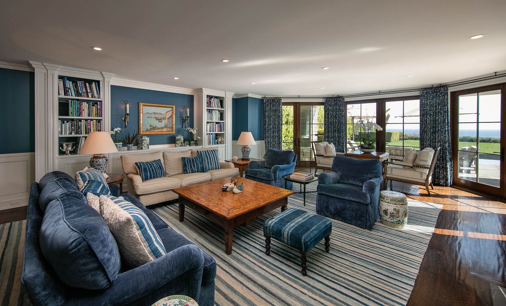 This living room concept reflects a great but not rigid arrangement. There is no need to adhere to the double-height room design style; yet, the stability and excellent composition will draw all eyes and admiration. An appealing and warm navy blue covers the entire space; all of these associations are interconnected and synchronized, such as the striped pattern on the carpets and throw pillows. Furthermore, the intertwining of blue and white demonstrates a rhythmic coordination.