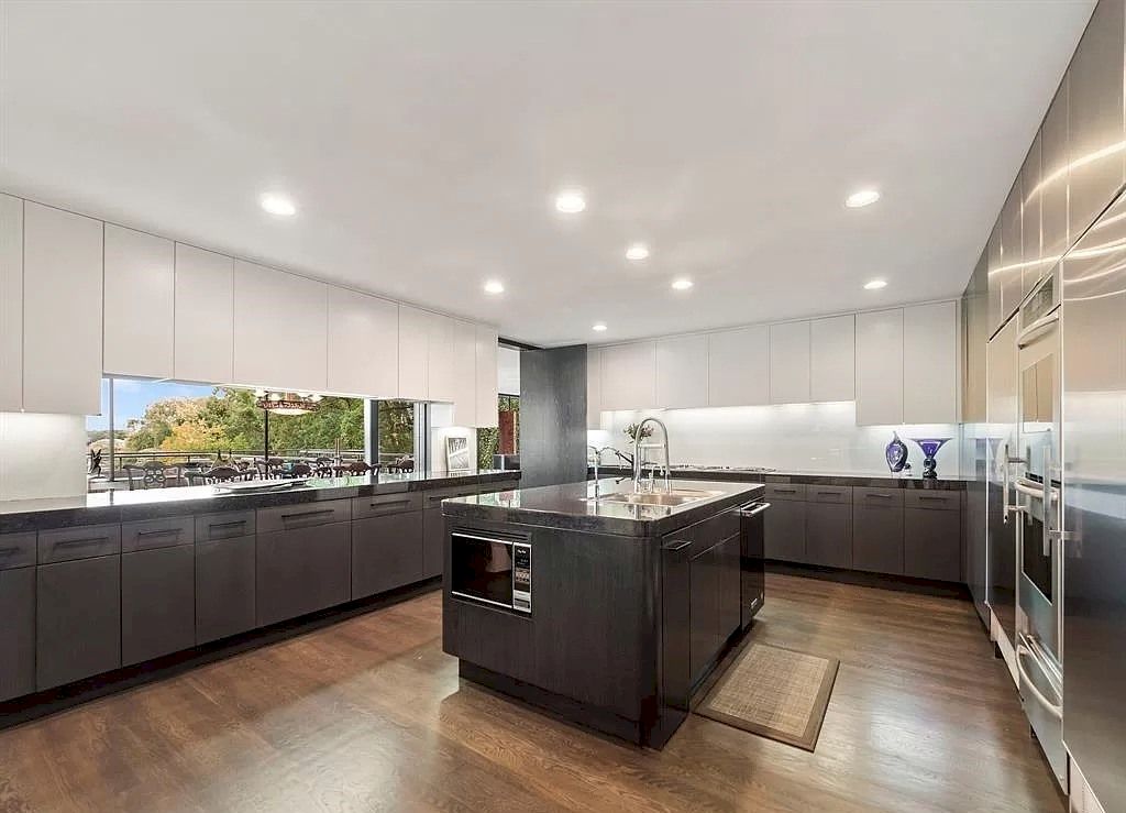 Another extremely contemporary and sleek kitchen design that uses wood, dark paint, and white accents to create a timeless and fashionable vibe. This kitchen could accommodate anyone's life; it feels quite one-size-fits-all, in a nice way! Wooden cabinets and counters add a fantastic amount of warmth, while gray is functional and white brightens the area. 