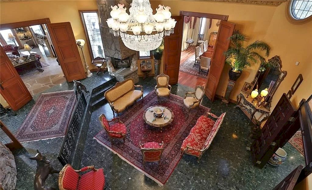 The red, wood, and black tile palette in this living room is tied together with a traditional rug. A room with three different color hues, each with a different color tone, but joined by a red carpet, which makes a strong connection and helps the room to feel warm. Despite the lack of vivid colors in the furnishings, the big area and brilliant lights ensure that the room is always bright.