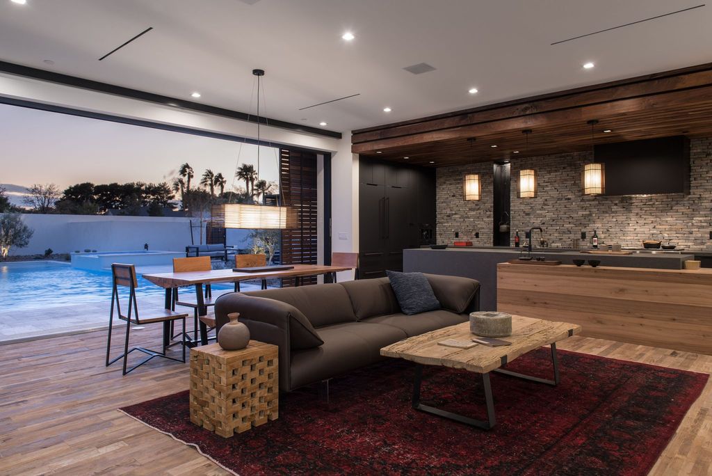 The owner purposefully did not allow a lot of light into this room. This is a living room that combines rustic and modern design elements. On one side, the design is sleek and futuristic, with glossy paint and moving doors. The wall, on the other hand, is brick-tiled, and the teapot is antique-styled with imitation stone material. The dark rug will add to the nostalgia while also providing a nice touch.