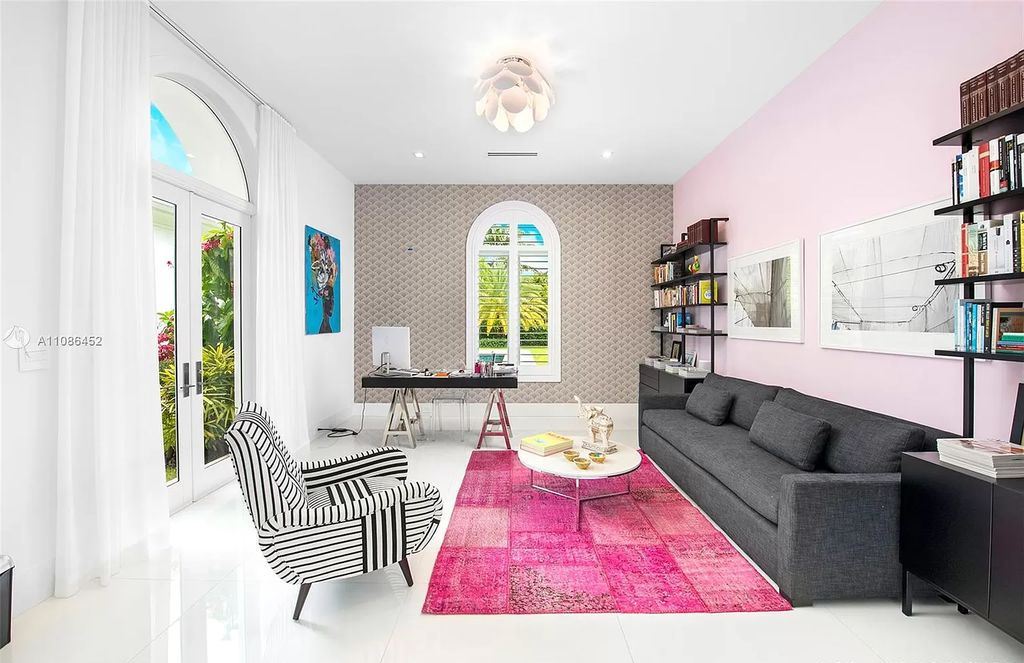 With touches of painted walls and a pink rug in two different tones, this living room atmosphere is artistic and lovely. The checkered pattern on the sofa and the playful wallpaper add to the candy living room. The arched main door is also a lovely feature. The center table and lighting in this living area demonstrate the attentive choosing.