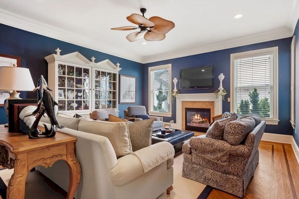 This traditional living room is elevated by the dark navy blue walls. This blue paint creates a strong background for other decorations and arrangements in the room. Natural light enters through the windows and is reflected by the light-colored furniture. The homeowner broke up the monotony of blue and white by incorporating brown and leopard prints into the mix. These characteristics reveal one's personality.