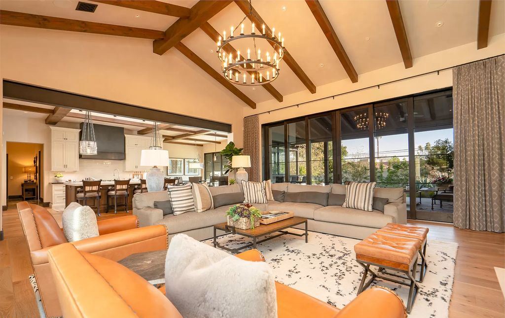 In these eclectic living room ideas, we appreciate the seamless harmony between the color of the chandelier and the color of the sofa's leather. While the overall building is ancient, with the spire and oak beams, the inside follows the current minimalist trend. The main entrance is designed to let in as much natural light as possible, and it is slender, simple, and youthful.