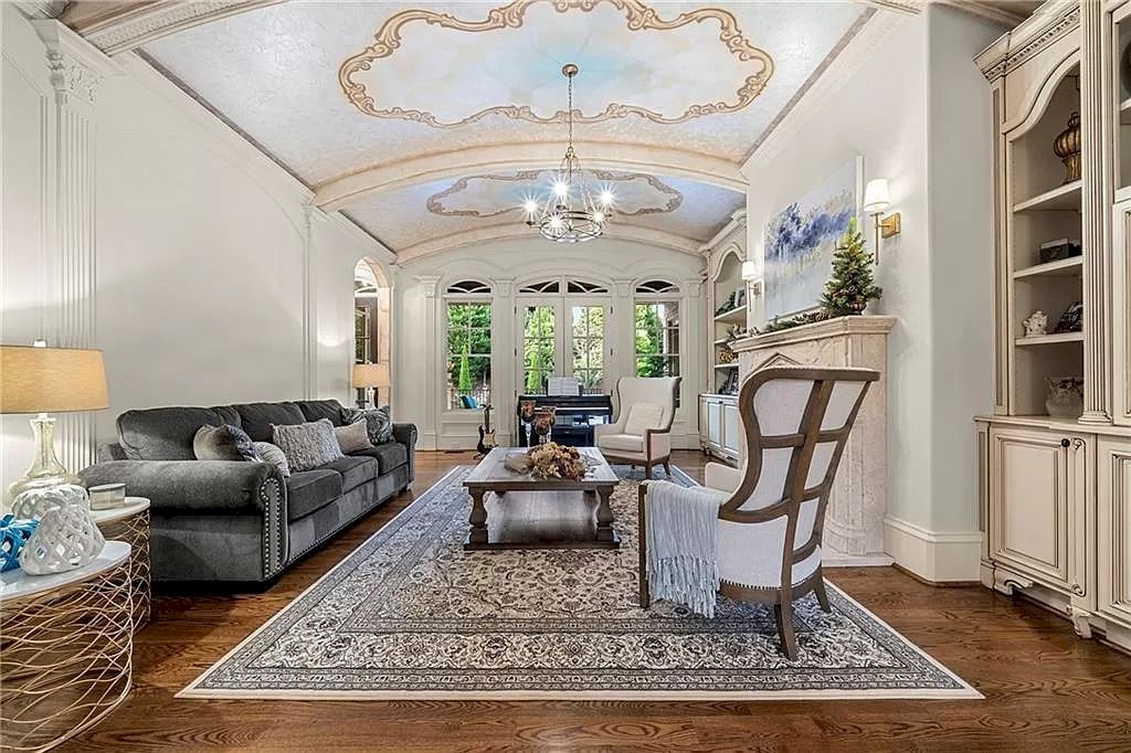 The navy blue ceiling in this bright living room is complemented by a cloud-like color scheme. A delicate, smooth flourish has been generated by a table lamp with a birdcage-shaped design and a shelf to keep cream-colored accessories. Meanwhile, the grey couch provides a sense of balance and harmony with the other hues.