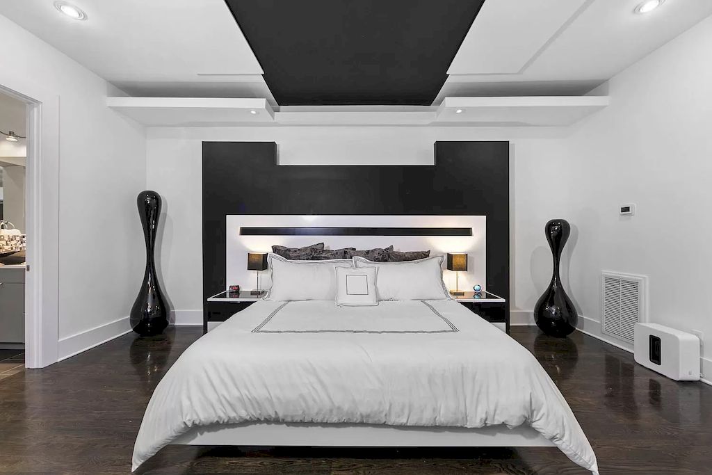 The bedroom ceiling is divided into black and white sections alternating with black in the middle as creating a smooth path leading to your cozy bed. The bed with an extended black and white headboard both creates a focal point and becomes a place to display some of your favorite items, or a modern night light set.