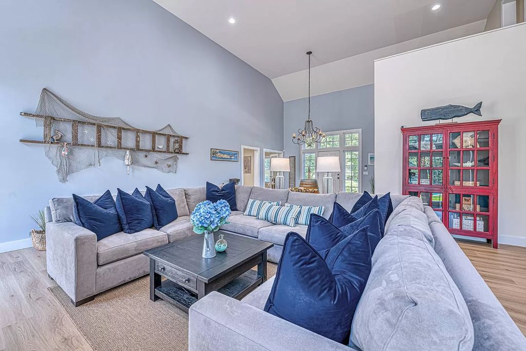 This living room's entire interior design is based on a single concept. The wall is painted blue like the calm sea. It is also embellished with fish nets and fun fish. The gray velvet sofa set and dark blue pillows are the ideal color and layout combination.