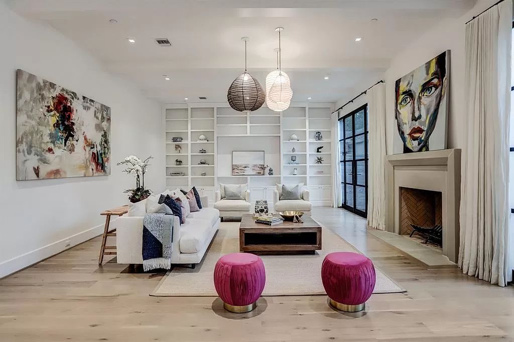 Light raspberry and white combo is an unexpected and stunning pairing that adds a playful vibe to a living room, like in this striking design above. A pair of ottomans in a deeper shade of raspberry brings balance to the white tones used throughout the rest of the room.