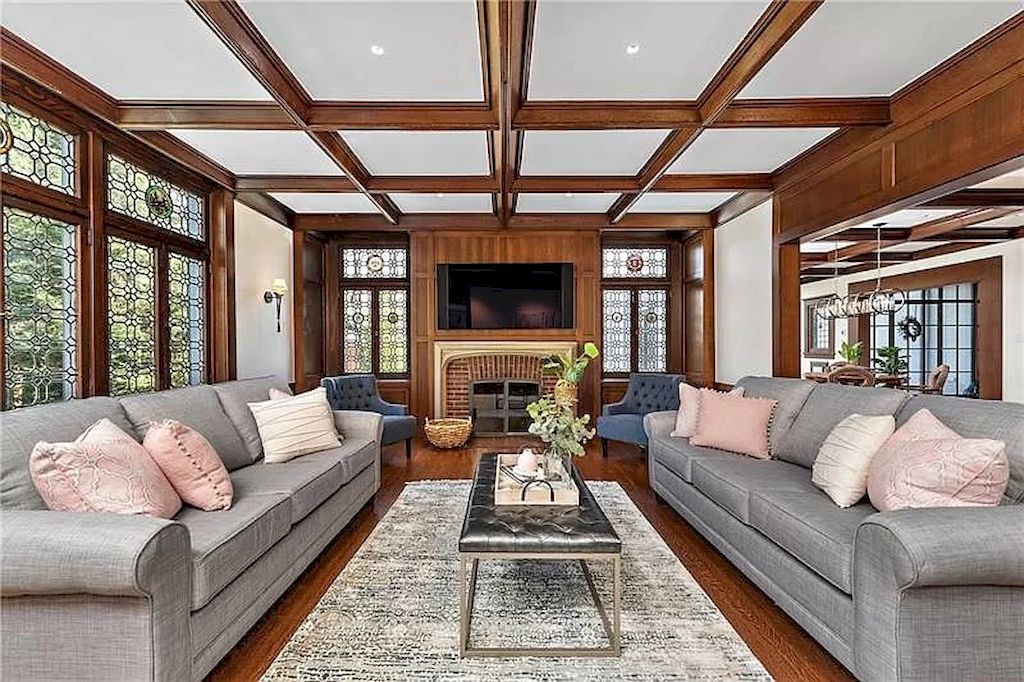 Modern living room with solid wood architecture and modern features, including a gray sofa set on tan silk fabric. Soft, gentle pastel pink pillows adorn the strong space. A gray chair can be brought to life with attractive shades. This arrangement exhibits a good color balance and interweaving.