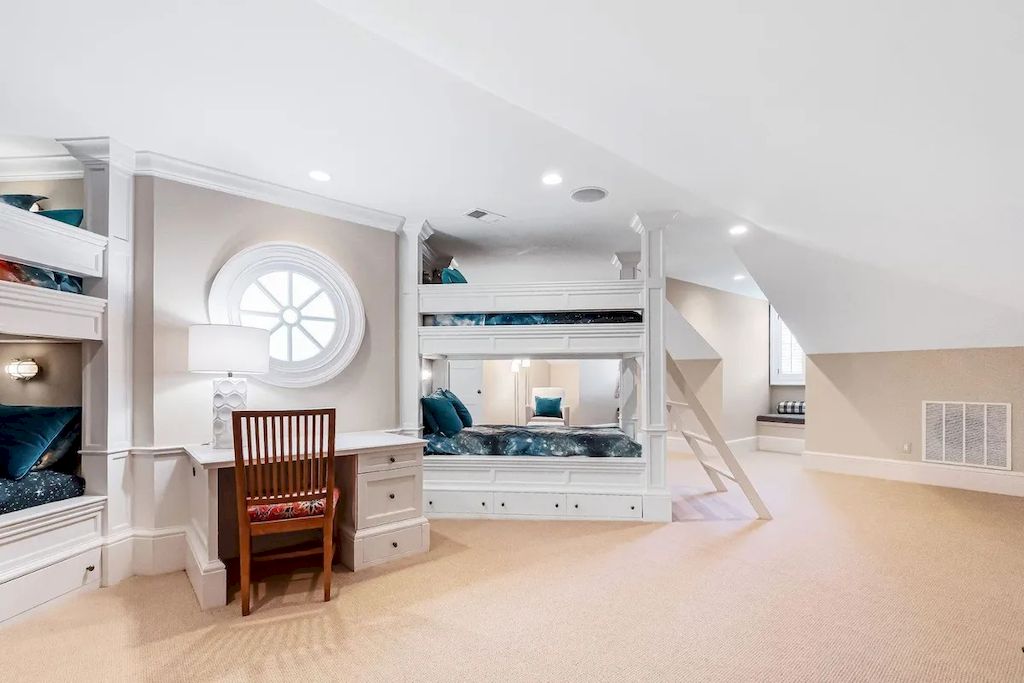 Bunk beds are decorated in a cheerful modern white in this adorable bedroom, which also features a round, unusual window and neutral grey walls.