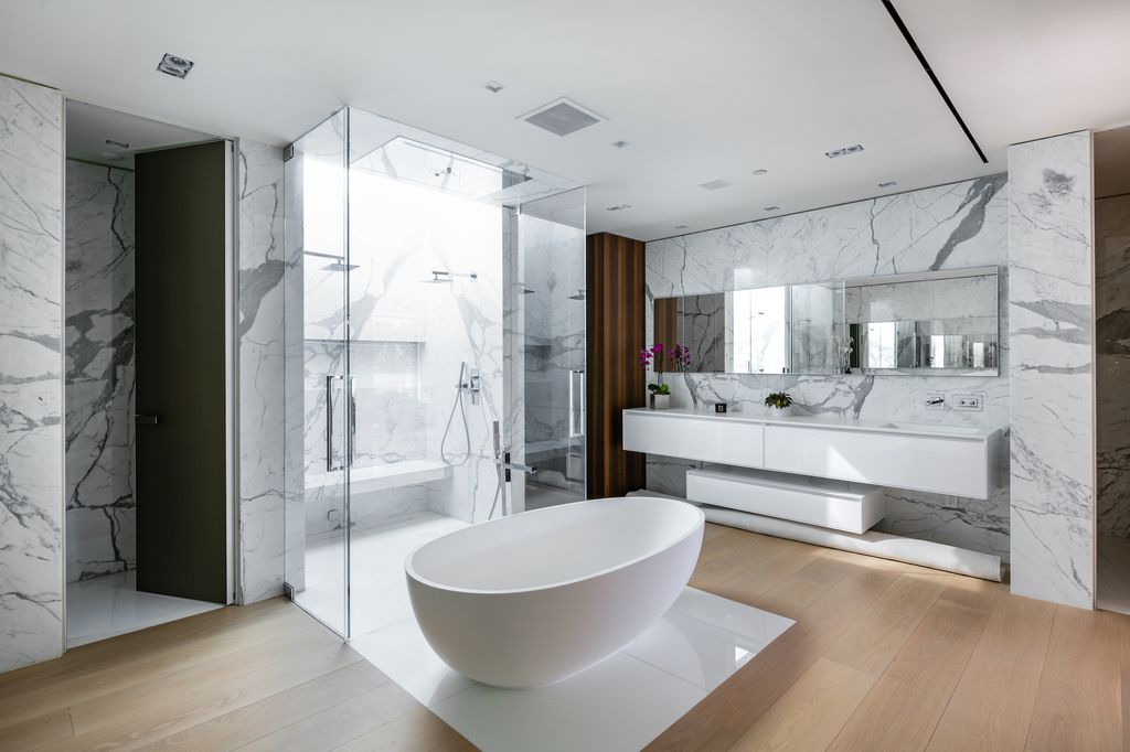 For a clean, uncomplicated bathroom backsplash, cover the wall behind your vanity with large tiles. A pristine white and gray backsplash constructed of large-scale ceramic tile sparkles in this bathroom. The sleek symmetrical design that repeats on the slate floor underneath is completed with clean white grout.