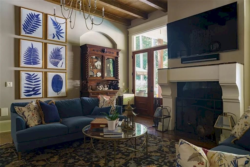 The blue sofa and white walls with shimmering gilt frames give the living area a contemporary atmosphere. The space feels more balanced and cozy thanks to the contemporary round coffee table and plush velvet carpet.