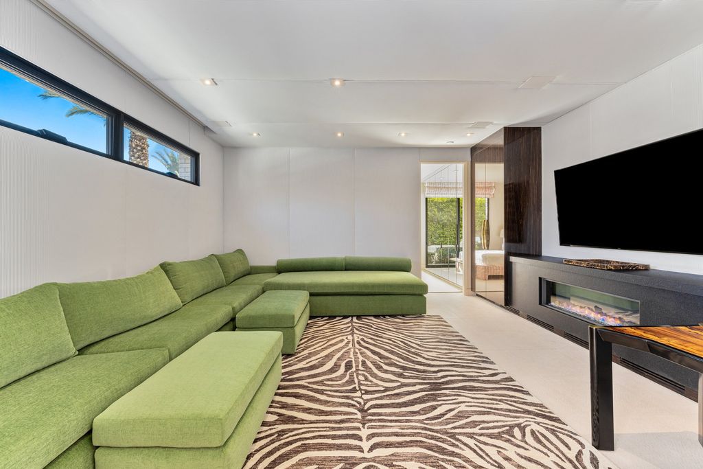 This simple and intimate green couch takes pride in its position in this living room. This generous size covers and spans much of the room, lending a cohesive and relaxing feel to the entire space. White walls and earthy rugs complement the green couch. The unity of minimalist design encompasses the concept of the entire architecture as well as the shape of the interior.