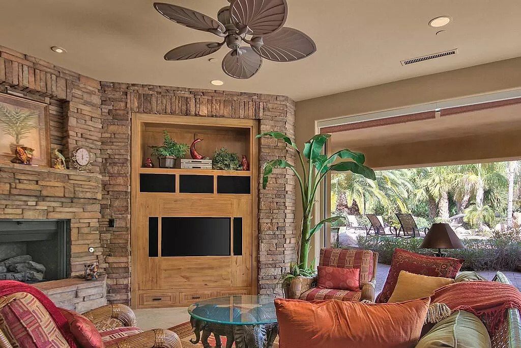 The arrival of green from nature in a living room with brown tones helps to relieve all stress and fatigue. In a different corner, a basic, rustic fireplace and built-in wood cabinets are used to display gathered artifacts ranging from flower spots to metal clock. Set of sofa in warn red hue with meticulously handcrafted metal drinking table makes this living room become rustic than ever.