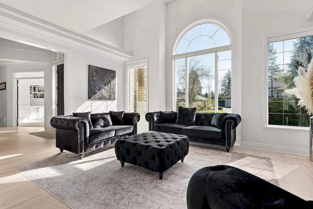 They made the room spacious and airy by using minimal furniture. Pure white paint and round arched windows soften the living room. They added light to the room by orienting the house to receive sunlight and installing glass windows to absorb natural light. The black chesterfield couch set adds a touch of elegance to the minimalist living room.