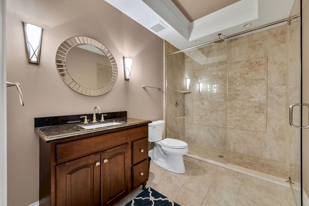 This bathroom's design successfully combines modern and nautical elements. Clean edges and a modern, neutral color scheme refresh the design while giving it a slight nautical flair. A more laid-back, beach vibe is added with the metal cage sconce and round rope mirror.