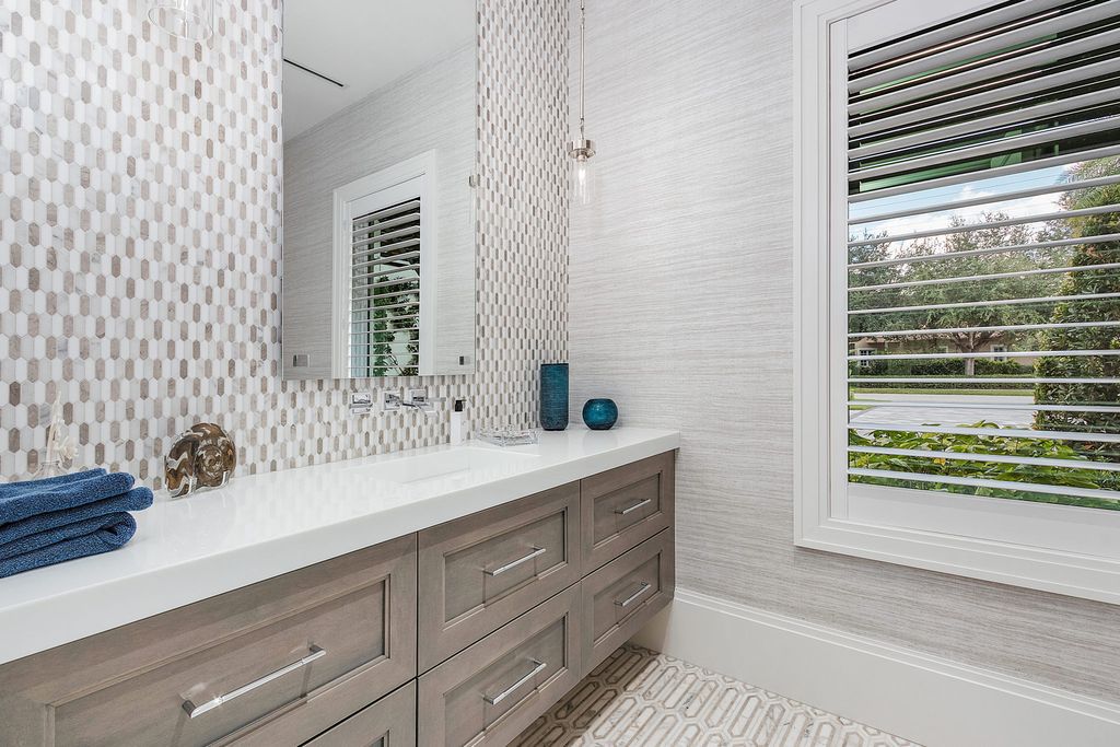 Moorish features, such as a shapely tiled backsplash wall, can contribute to an internationally inspired aesthetic in your bathroom. The arabesque tile design compliments a borderless mirror by repeating a motif prominent in Moroccan architecture. Each tile stands out because to the bright white grout.