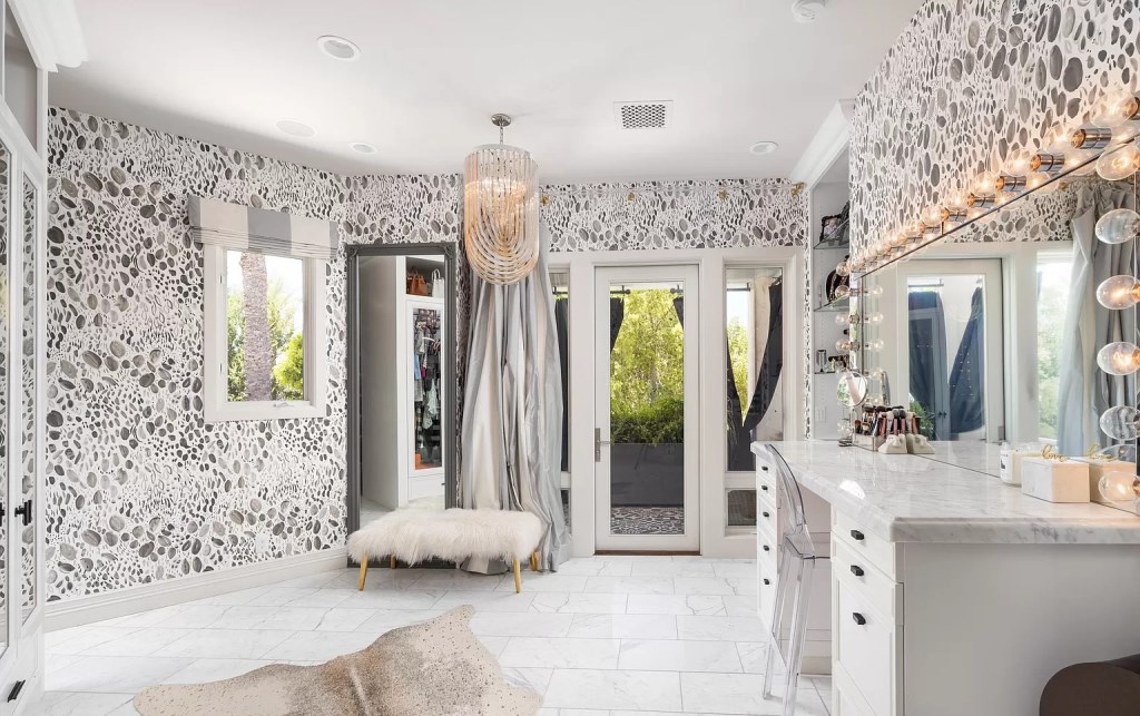 This bathroom design Interiors' large ottoman offers a spot to change into your daytime clothes. The Roman window treatments and marble flooring and countertop each feature veining that matches the color of the gingham pattern, creating a lovely design aesthetic.