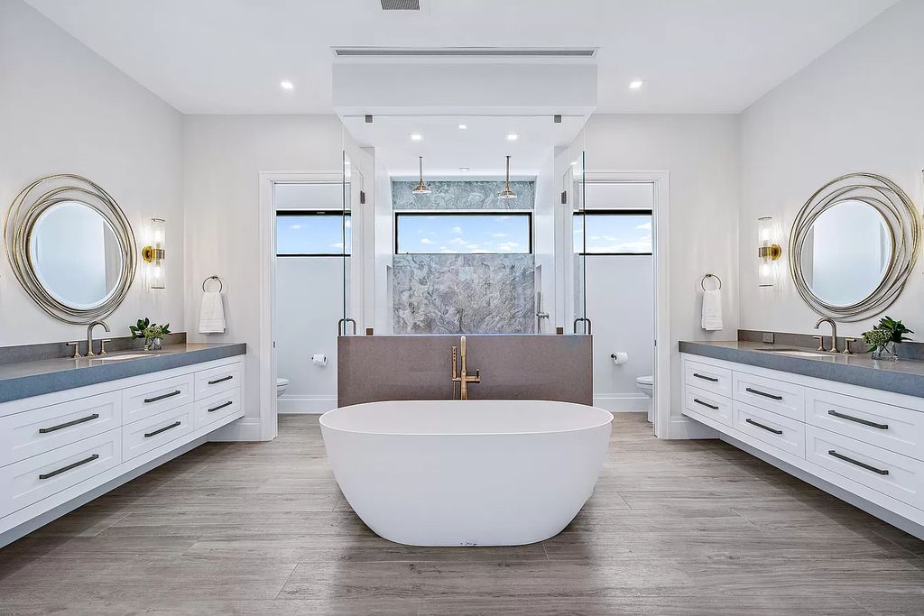 One of the effective ways to bring elegance to large bathrooms is to install furniture that ensures symmetry. A large bathroom is made up of two smaller units with two separate toilets enhancing privacy, a wall-mounted hand basin with drawers, and a unique mirror. This bathroom idea is extremely suitable and is a smart idea for large families. A perfect bathroom space with attention to detail.