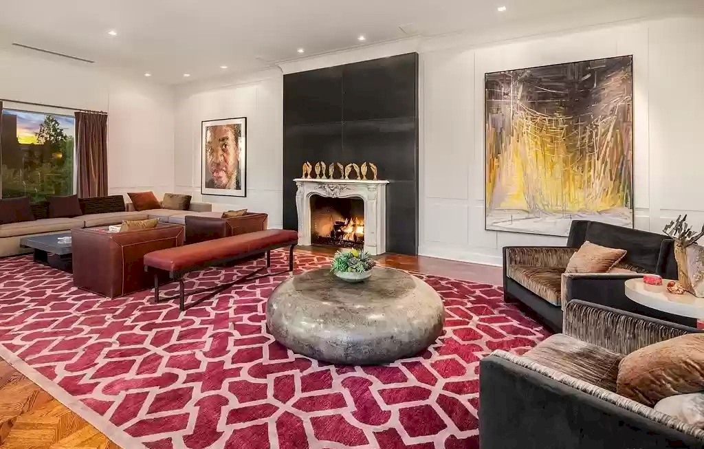 Red is a color that many people love, and this Vintage Living Room Idea is redecorated in shades of red. The red chair matches the pillows on the couch as well as adds some warmth to your space with its welcoming hue. A geometric pattern red rug is thrown underneath as background for the round-shaped stone coffee table that suits any home décor style.