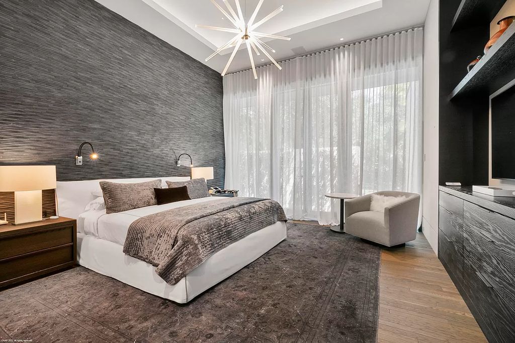 Color-inspired bedroom design, like this one in Jupiter, Florida. A unique gray panel wall is the ideal backdrop for other soft, light colors. Meanwhile, the use of yellow light from the table lamp and wall lamp adds to the room's convenience and warmth.