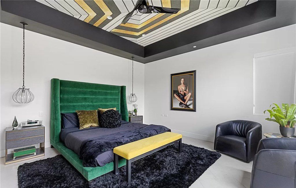 Add an artistic touch by incorporating a cobweb ceiling and a colorful bed. The focal point of this design is an enticing black fur rug and matching cushions. Silver pendant lights are also a must-have accessory.