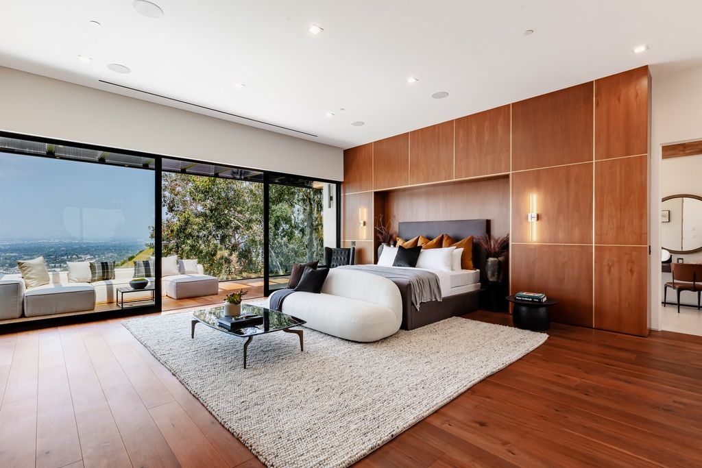 Using the right placement and lighting, the designer turned this bedroom into a focal point. Only a large glass door frame allows you to "embrace" the beautiful scenery outside. Snow white furniture and modern wooden walls are unmistakable.