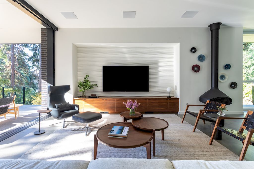 Furniture plays a significant role in expressing the style of a home, particularly in this mansion located in Oregon, US. The wooden chairs and tables are a perfect fit for the open space and provide a refreshing and relaxing atmosphere. The coffee tables, arranged in an attractive way, do not create a monotonous or repetitive feel. Moreover, the decorative false chimney also contributes to the overall symmetry of the room.