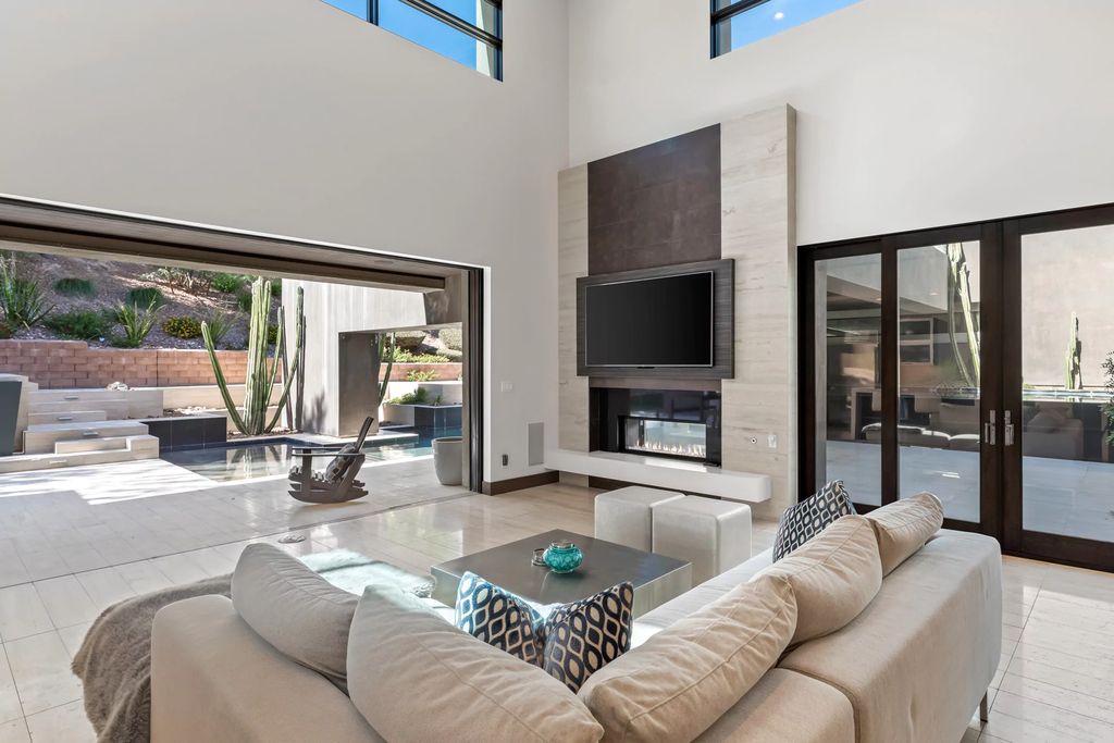 The fact that a fireplace and a television typically become the focal points of living rooms makes it challenging to make them function together. In this living room, the television is above and the fireplace is below. The TV appears to be the perfect complement thanks to the neutral color scheme and dark wood accents.