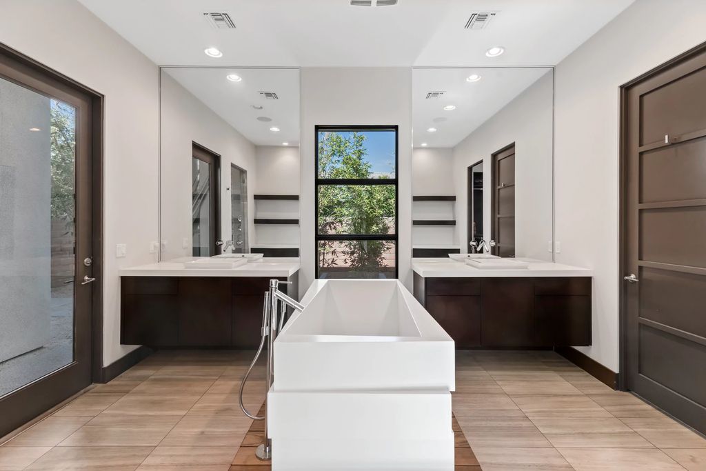 Bringing the rule of symmetry into the bathroom design idea with the appearance of a luxurious bathtub in the middle of the two hand basins. This structure seems to divide the bathroom into two separate halves but still connects to each other. Two large mirrors on either side of the window create reflections to the end of the room, making the overall look much more spacious. This Bathroom Layout Idea is quite suitable for families with many members.