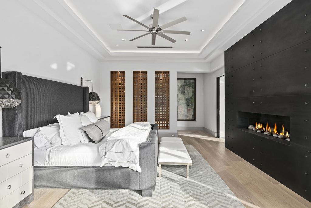 Give your bedroom a hotel feel with cozy white sheets and an assortment of complementary throw pillows. Cool tones such as the shapes of gray, and black of the built-in fireplace cover make this bedroom more modern and luxurious than ever. An idea is quite suitable for strong gentlemen.