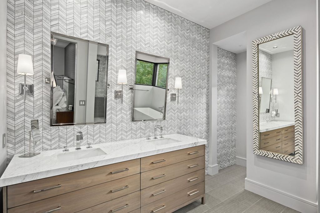 Of course, there are other bathroom vanity designs to pick from, such as a rustic wooden design or a conventional metal unit with exposed framework. This vanity design adopts an uncluttered, minimalist style, taking influence from modern cabinet designs such as those seen in kitchens. It is defined by a smooth, white countertop, flush gray drawers and cabinets, and a wide mirror with integrated shelves and lighting. A central unit like this is an excellent choice for bathroom organizing ideas.