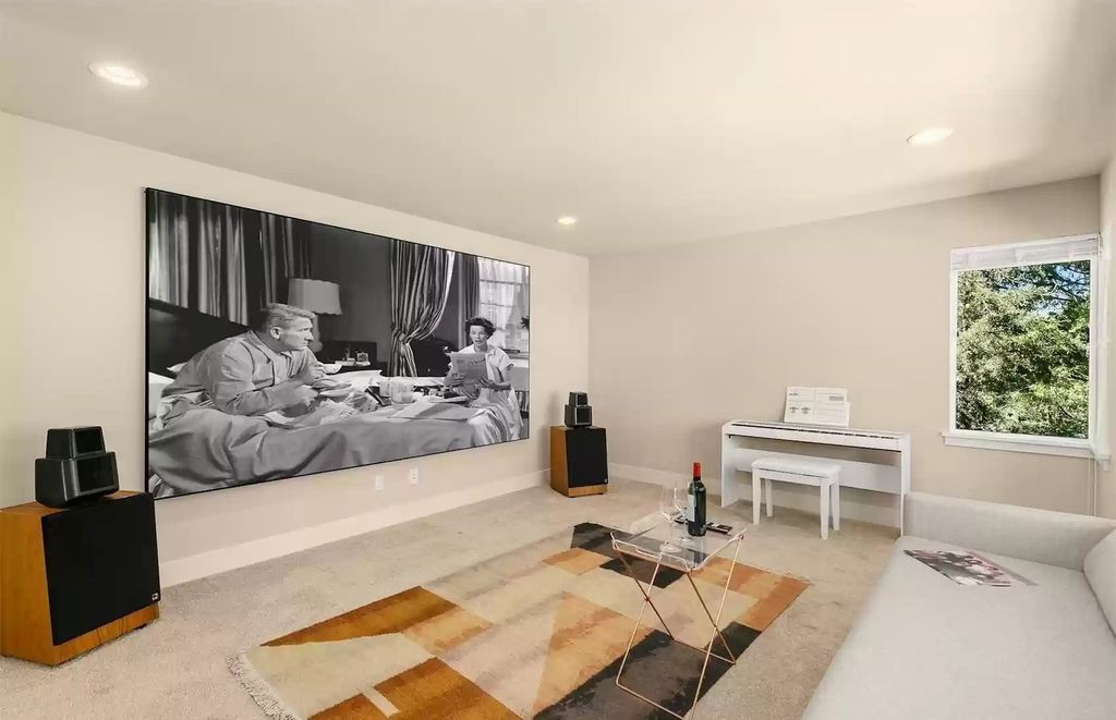 Neutral tones are combined smoothly and prominently in this living room. A warm backdrop is created by the gray carpet with geometric patterns. While the wall only needs to be adorned with a massive TV. This is the ideal relaxing space for any family.