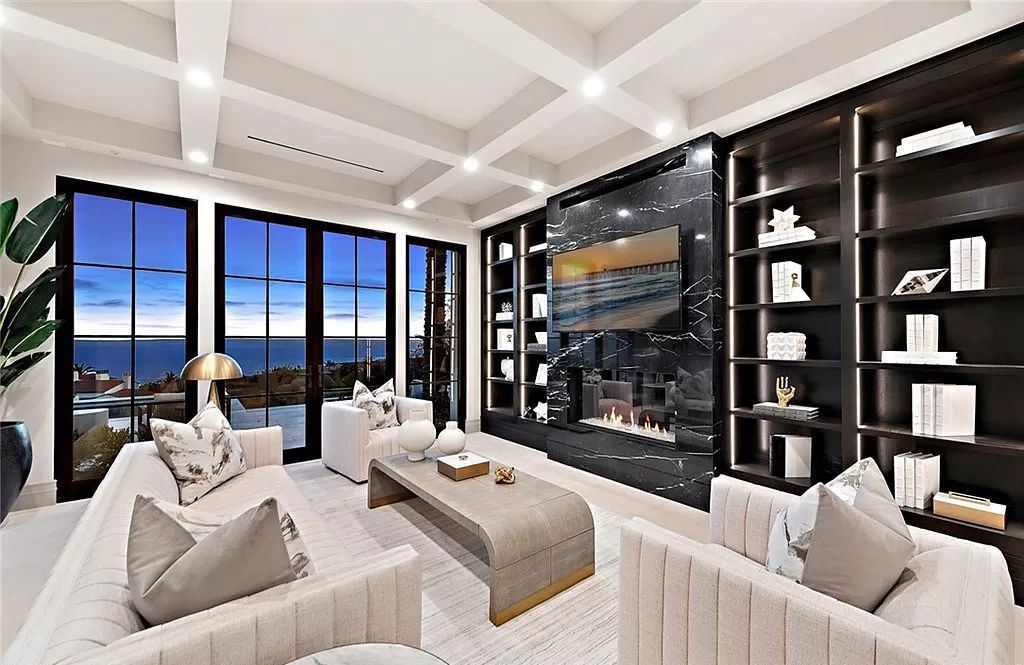 Black furniture is paired with stark white walls in this monochromatic living room. The extended sofa serves as the room's focal point, and it is paired with the wall-mounted black bookcase.