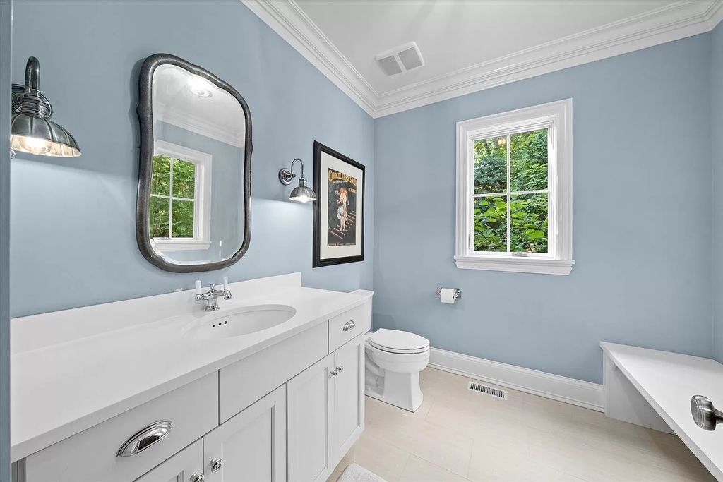 With a vivid blue backsplash, you may create a relaxing getaway in the comfort of your own home. The stunning linear tiles inspire ocean seas with varying tones of soft powder navy. The to-the-ceiling backsplash complements the marble-framed mirrors' delicate gray veining.