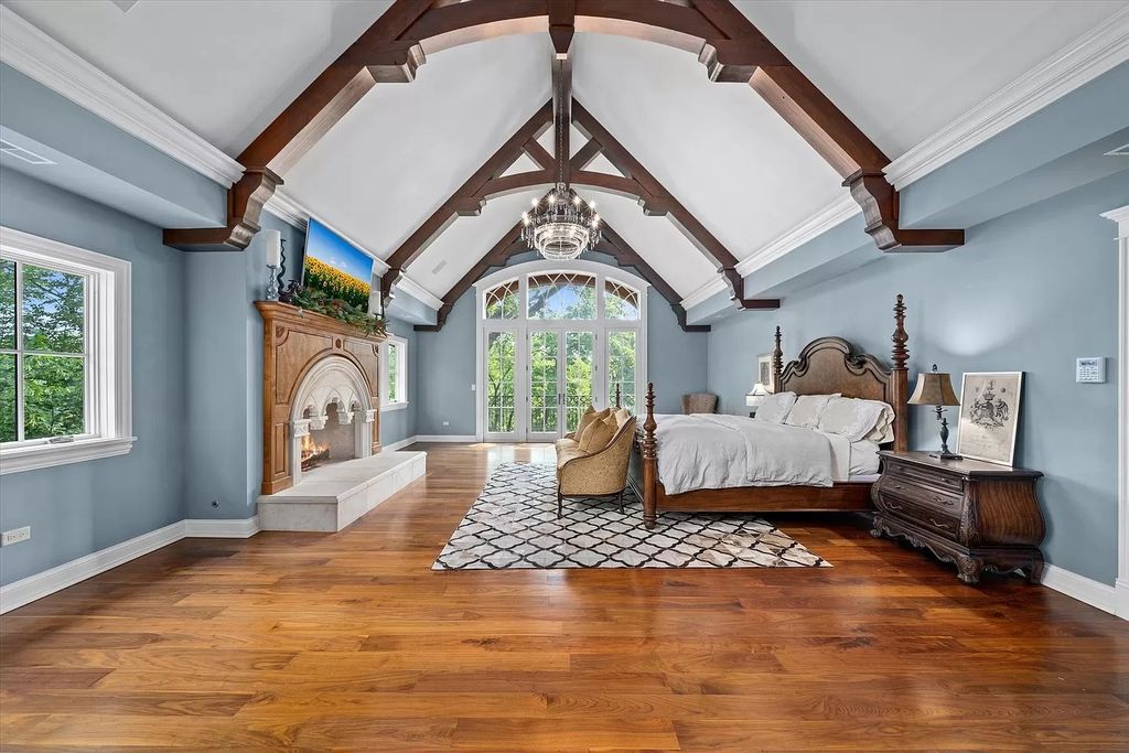 Wood planks, a built-in fireplace as the focal point, a vaulted ceiling with wooden beams, and classic wood nightstand combine to create the perfect farmhouse style for the bedroom. The overall look should be more complete thanks to the appearance of Erie blue and white hues chosen for the paint color of the walls and vaulted ceiling.
