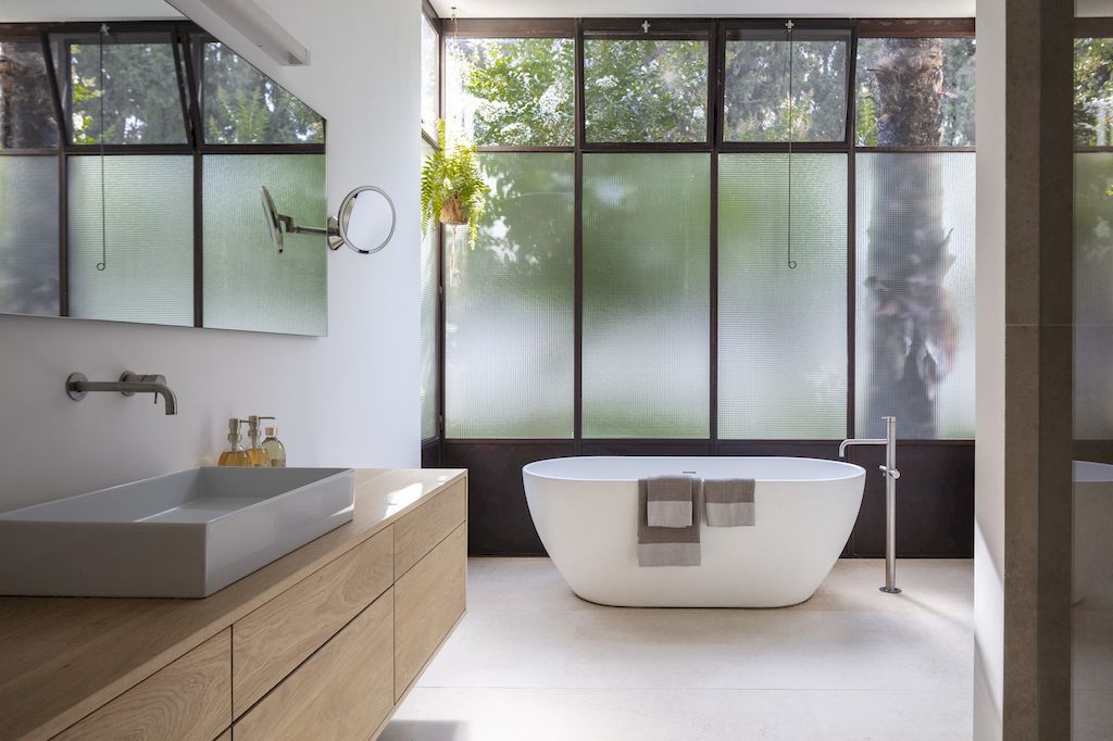 Enjoy yourself if you are following a modern, youthful design trend. Blatman Cohen Architecture Design placed the bathtub right next to the Obscure glass window, as both privacy and light are desired.