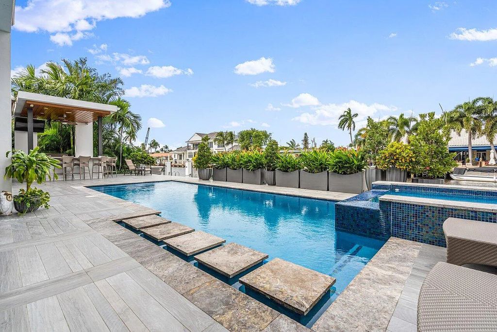 2881 NE 27th Street, Fort Lauderdale, Florida is a modern and sophisticated residence features a floor-to-ceiling stone stacked fireplace, large sliding doors leading outside, and full connectivity to the rest of the open concept living areas.