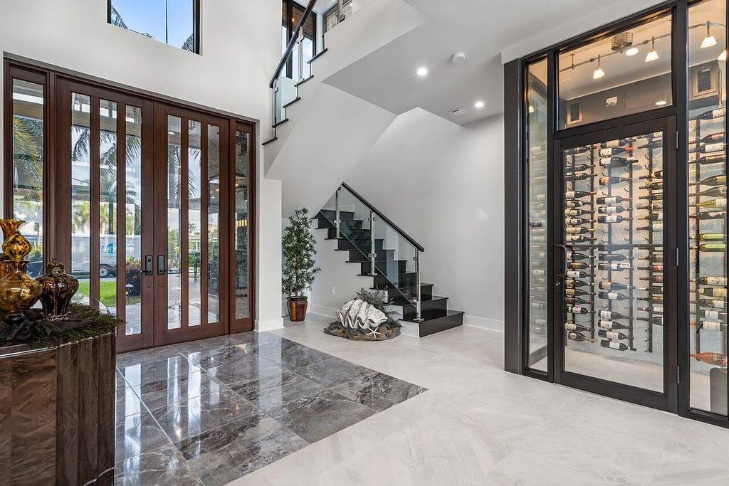 2881 NE 27th Street, Fort Lauderdale, Florida is a modern and sophisticated residence features a floor-to-ceiling stone stacked fireplace, large sliding doors leading outside, and full connectivity to the rest of the open concept living areas.