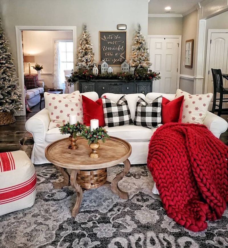 The enormous Christmas tree that faces the door and glitters in the corner serves as the focal point of the interior's ivory and white living room. A glittering attraction is produced by the assortment of metallic balls dangling from the branches. Other than the stunning tree, the holiday decorations are straightforward and organic—red peonies, crimson amaryllis, evergreens, and magnolia greenery.