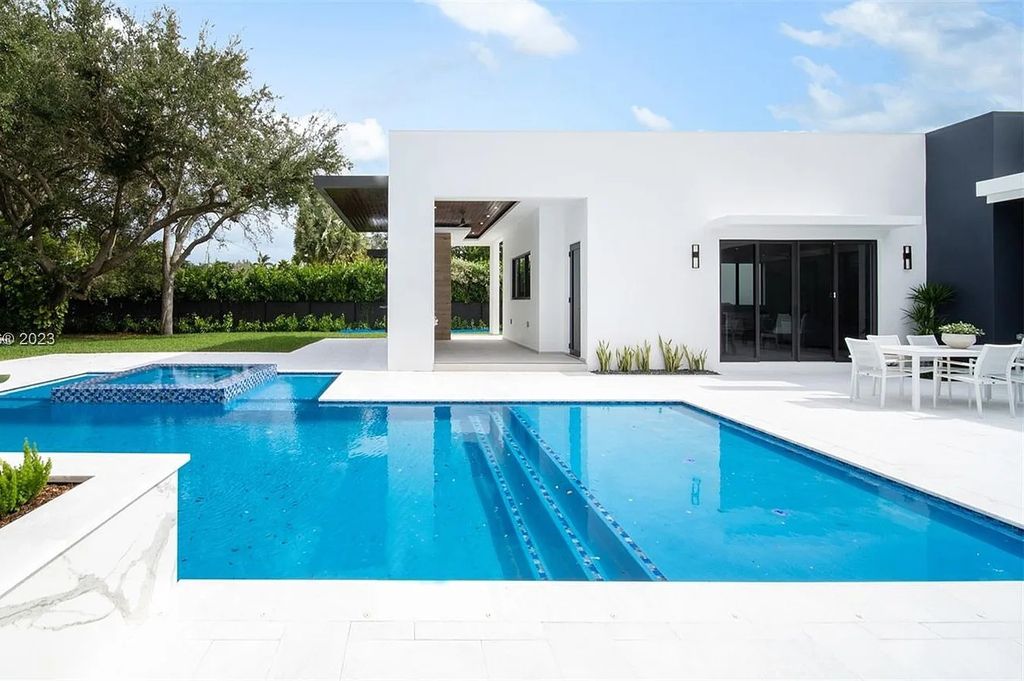 9765 SW 110th Street, Miami, Florida is an exquisite modern new construction built among stately palms and mature oak trees on a quiet cul-de-sac, experience the ultimate South Florida lifestyle lounging around the 38' pool with spa and 3 beaches.