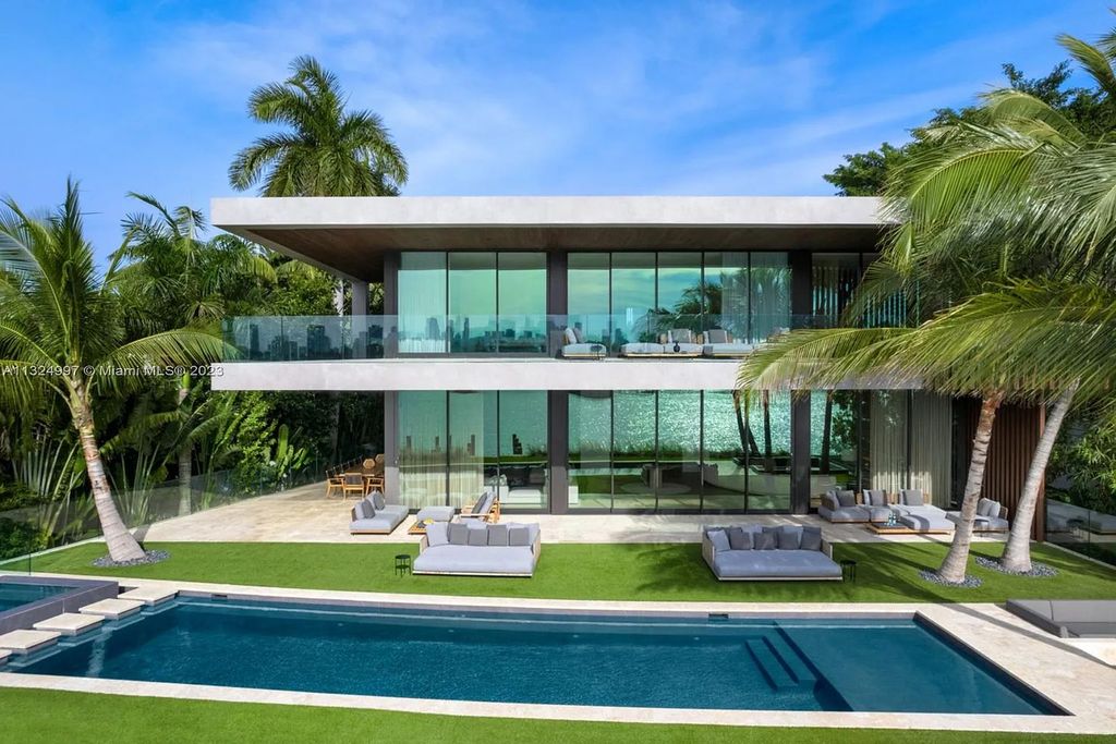 28 W Di Lido Drive, Miami Beach, Florida is stunning home where relaxed island living meets worldly sophistication, incredible features include 12ft ceilings, column-free living, 54ft of automated glass, media bookshelf, wine bar, & vapor fireplace highlight the textured travertine and white oak palette.