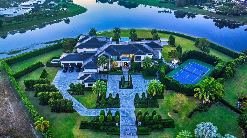 This 7-bedroom, 12-bathroom lakefront estate is a private oasis situated on a 2.6-acre point lot with 600 feet of waterfront in Delray Beach, Florida. 9480 Bent Grass Court features glass walls that connect the lake side of the home to expansive terraces, a lanai with a summer kitchen, and an infinity pool with a sun shelf.
