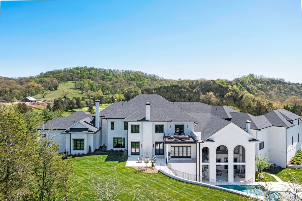 This luxurious home is located in a gated community and boasts 5 bedrooms, 9 bathrooms, and 19,561 square feet of living space on an 11-acre lot. The grand entrance leads to a spacious living room with stunning views of the green lawn outside.