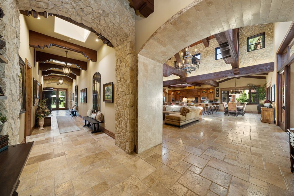 Indulge in the lavishness of a sprawling Mediterranean estate located on 4.71 acres in the sought-after Rancho Santa Fe. This private gated property boasts a grand Tuscan villa with a circular drive featuring a serene fountain and four separate stone and vine-covered structures surrounded by lush greenery.