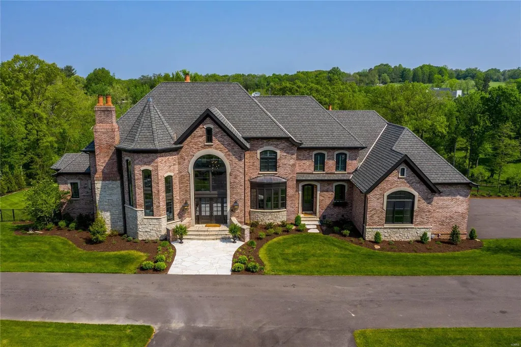 23 Brookwood Road Home in Saint Louis, Missouri. This remarkable residence showcases a grand two-story foyer, a library-paneled study, an elegant dining room, and a stunning great room with Palladian windows and a wet bar. The designer kitchen boasts quartzite countertops and commercial-grade appliances, while the master bedroom suite offers a marble bath and a private deck. 